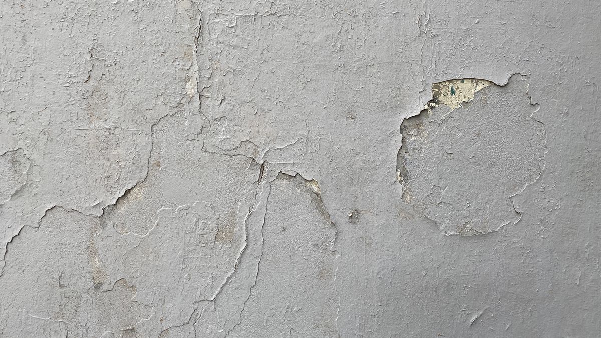 Close view of an interior wall surface with weathered layers of paint and plaster