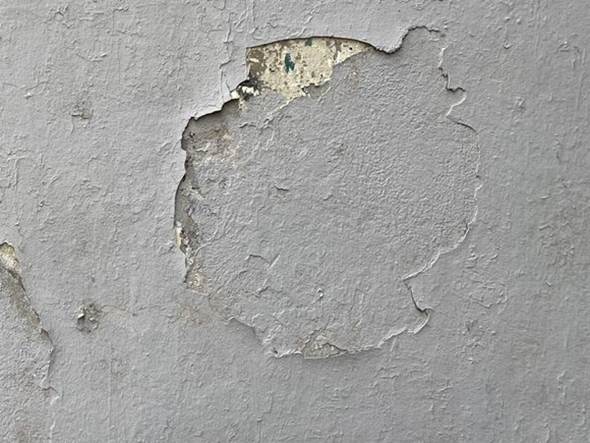 Detail of a painted building surface with layered coatings and visible wear
